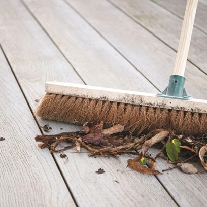 Broom sweeping leaves on a floor decking